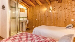 A wooden-paneled room with a bed, a small sink, and a glass shower enclosure. - Chalet, 350m from ski lifts, sauna, terrace, fireplace or stove, parking, tv, 100m² (Peisey-Nancroix)