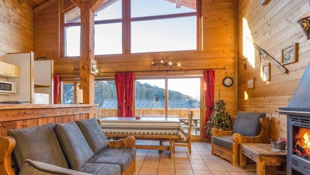 A cozy cabin interior with a wooden interior, a fireplace, a sofa, a dining table, and a view of the outdoors. - Chalet, 350m from ski lifts, sauna, terrace, fireplace or stove, parking, tv, 100m² (Peisey-Nancroix)