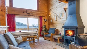 A cozy log cabin interior with a fireplace, wooden furniture, and a view of the outdoors. - Chalet, 350m from ski lifts, sauna, terrace, fireplace or stove, parking, tv, 100m² (Peisey-Nancroix)