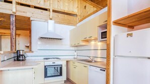 A compact kitchen with wooden cabinets, a stove, a dishwasher, and a microwave. - Chalet, 350m from ski lifts, sauna, terrace, fireplace or stove, parking, tv, 100m² (Peisey-Nancroix)