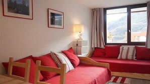 A room with two red sofas, a wooden chair, a small table, and a window with curtains. - 3rd floor, view ski slopes/mountain/ski slopes, balcony, tv, ski locker, 25m², Les Menuires (Les Menuires)
