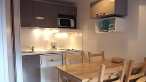 A compact kitchen with a microwave, a small refrigerator, and a sink. There is a wooden dining table with chairs. - 3rd floor, view ski slopes/mountain/ski slopes, balcony, tv, ski locker, 25m², Les Menuires (Les Menuires)