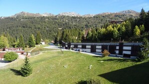 A grassy area with a building in the background, surrounded by trees and mountains. - 100m from ski slopes, 9th floor, view mountain, balcony, tv, 30m², Les Arcs (Les Arcs)
