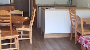 A compact kitchen with wooden cabinets, a sink, and a microwave. There are wooden chairs around a small dining table. - 100m from ski slopes, 9th floor, view mountain, balcony, tv, 30m², Les Arcs (Les Arcs)