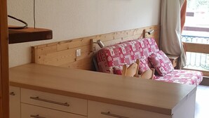 A cozy room with a wooden bed, a small desk, and a window with curtains. - 100m from ski slopes, 9th floor, view mountain, balcony, tv, 30m², Les Arcs (Les Arcs)
