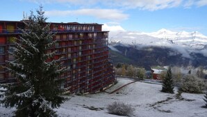 A multi-story building with balconies, surrounded by snow-covered ground and mountains in the background. - 100m from ski slopes, 9th floor, view mountain, balcony, tv, 30m², Les Arcs (Les Arcs)