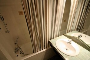 A bathroom with a bathtub, two sinks, and a shower.