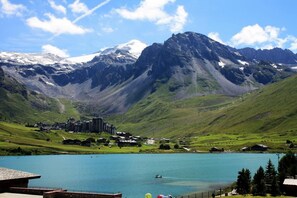 A mountainous landscape with a lake, buildings, and a clear sky.