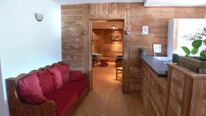 A wooden interior with a red sofa, a wooden counter, and a plant. - Terrace, parking, tv, ski locker, 67m², La Norma (Avrieux)