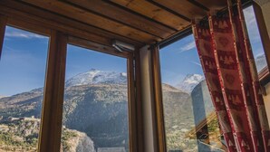 A room with large windows offering a view of a snow-capped mountain. - Terrace, parking, tv, ski locker, 67m², La Norma (Avrieux)