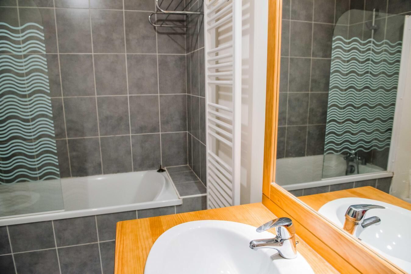 A bathroom with a bathtub, a sink, and a mirror.