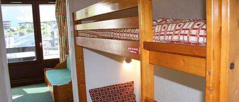A bunk bed with a patterned mattress, a bench seat, and a window with curtains.