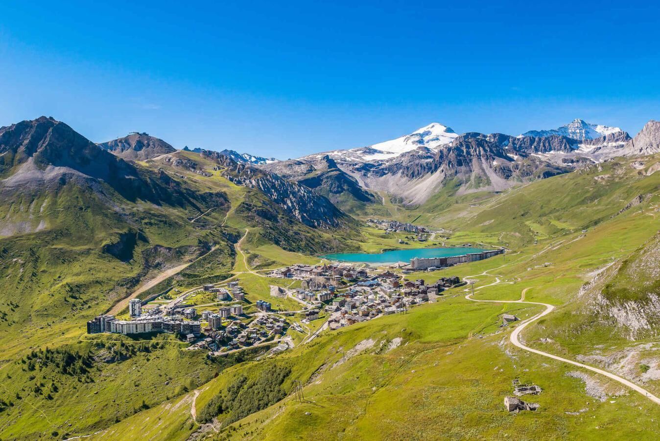 Et bjerglandskab med en by, bygninger, veje og en sø.
