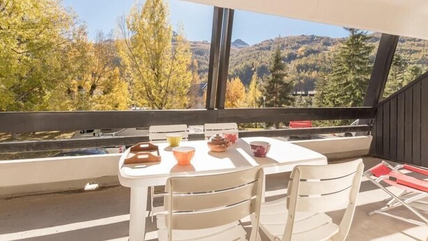 A balcony with a table and chairs, overlooking a forested hillside. - 350m from ski slopes, 1st floor, terrace, parking, tv, 56m², Serre Chevalier (SERRE CHEVALIER)