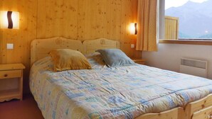 Ein Schlafzimmer mit Holzwandverkleidung, einem Bett, zwei Nachttischlampen und einem Fenster mit Vorhängen.