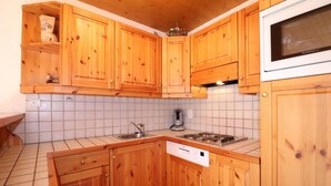 Eine Küche mit Holzschränken, einer Spüle, einem Herd und einer Mikrowelle.