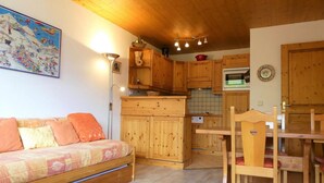 Ein gemütliches Zimmer mit einer Holzdirektiva, einem Esstisch mit Stühlen und einer Küchenzeile mit Holzausstattung und einem Herd.