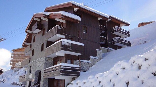Un hotel a più piani con balconi e facciata in pietra, immerso nella neve.