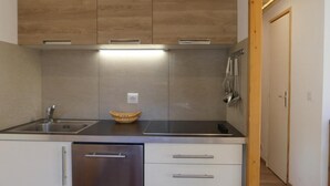 Una cucina compatta con mobili in legno, un lavello in acciaio inox e una lavastoviglie integrata.