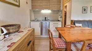 Una cucina compatta con zona pranzo, pensili in legno, lavello in acciaio inossidabile e tavolo con sedie.