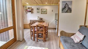 Una stanza accogliente con un tavolo da pranzo in legno, sedie, un divano e un angolo cottura.