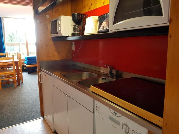 A compact kitchen with a microwave, coffee maker, and sink.