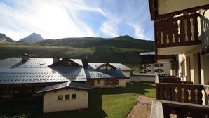 A cluster of traditional chalet-style buildings with sloped roofs, set against a backdrop of mountains.