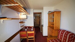 A compact room with a dining table, chairs, a cabinet, and a sofa.
