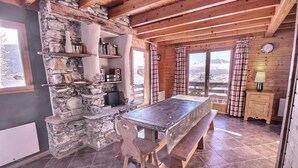 A rustic wooden cabin with a stone wall, a wooden table with benches, and a bookshelf. - Chalet, 350m from ski slopes, balcony, fireplace or stove, tv, 100m², Peisey-Vallandry (Landry)