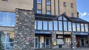 A building with a stone facade, large windows, and signage for 'Balcons du Soleil 1' and 'Maison de Peyragudes'.