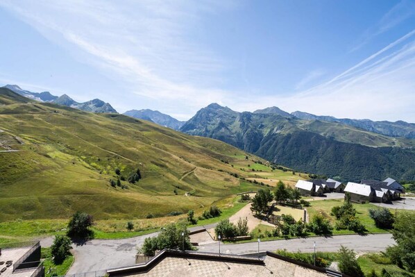 A mountainous landscape with a row of stone buildings, likely a hotel, with a clear sky and distant mountains.