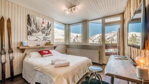 Ein Schlafzimmer mit Bett, Schreibtisch und Bergblick.