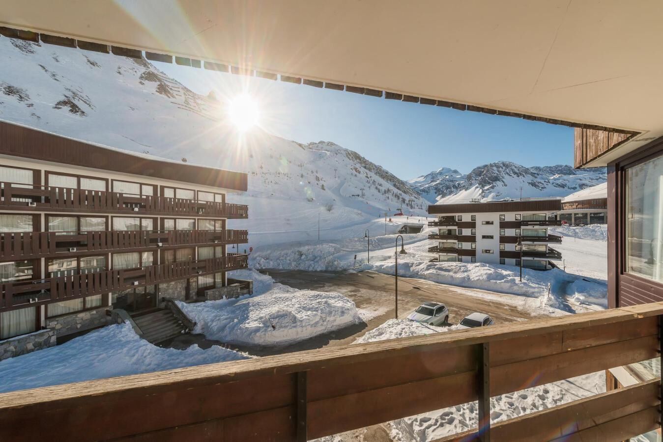 Ein modernes Gebäude mit mehreren Balkonen und einer Skipiste im Hintergrund.