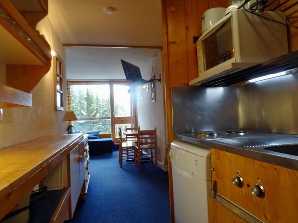 A compact kitchen with wooden cabinets, a microwave, and a sink.