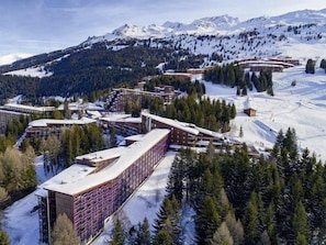 A ski resort with multiple buildings, including a large hotel with a curved facade and a smaller lodge.