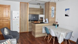 A compact kitchen with wooden cabinets, a dining area with a table and chairs, and a small island with a sink.