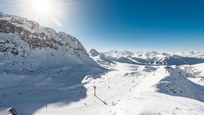 Un paysage de montagne enneigé, avec des pistes de ski et un ciel dégagé.