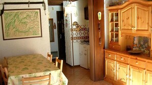 Un coin repas avec une table et des chaises, une cuisine dotée de meubles en bois et d’un réfrigérateur.