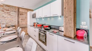 Une cuisine moderne avec des armoires blanches, un mur d’accent en bois et un pare-feu turquoise.