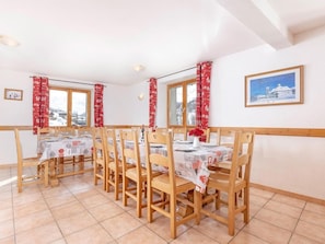 A dining area with wooden chairs and tables, red curtains, and a framed picture on the wall. - Chalet, wifi, terrace, fireplace or stove, parking, tv, ski locker, 190m², Les Menuires (Les Menuires)