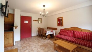 A compact living space with a dining area, a sofa, and a kitchenette.