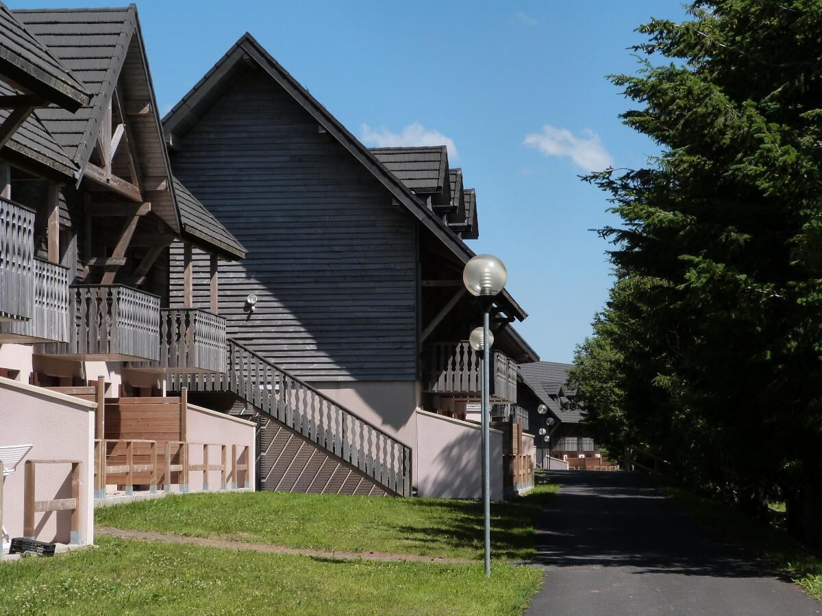 A traditional wooden building with a sloped roof, a balcony with a railing, and a street lamp.