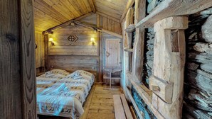 Une chambre rustique aménagée dans une cabane en bois, avec un lit, une petite table et un mur en pierre.