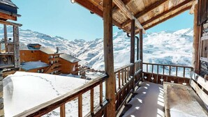 Un balcon en bois donnant sur un paysage enneigé, avec des bâtiments en arrière-plan.