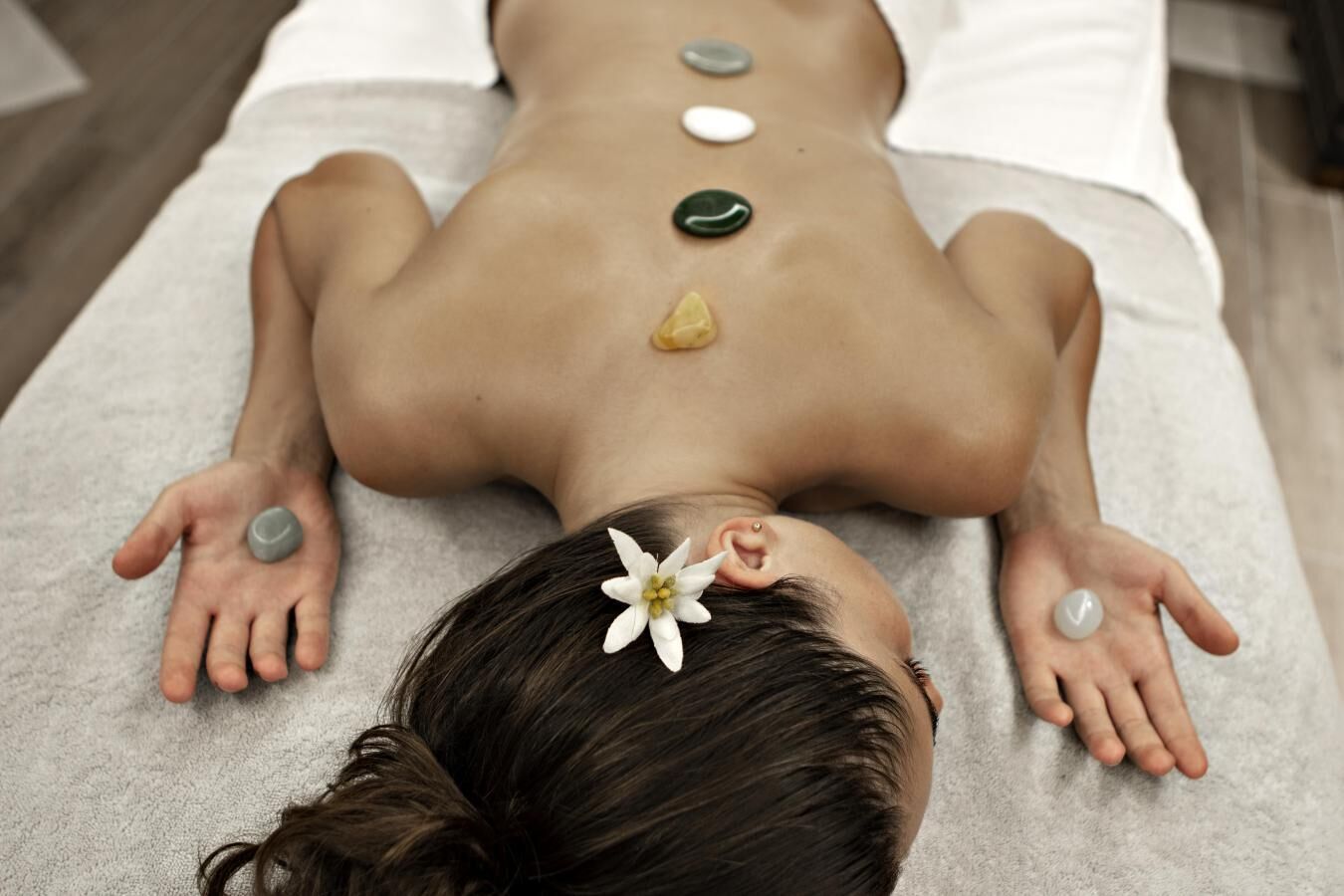A person receiving a back massage with stones placed on their back.