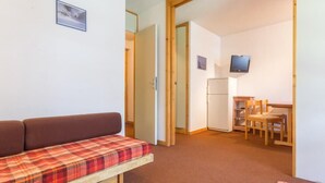 Une pièce confortable avec un canapé, une petite table et un téléviseur.