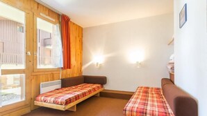 Une chambre avec deux lits, une fenêtre et une porte.