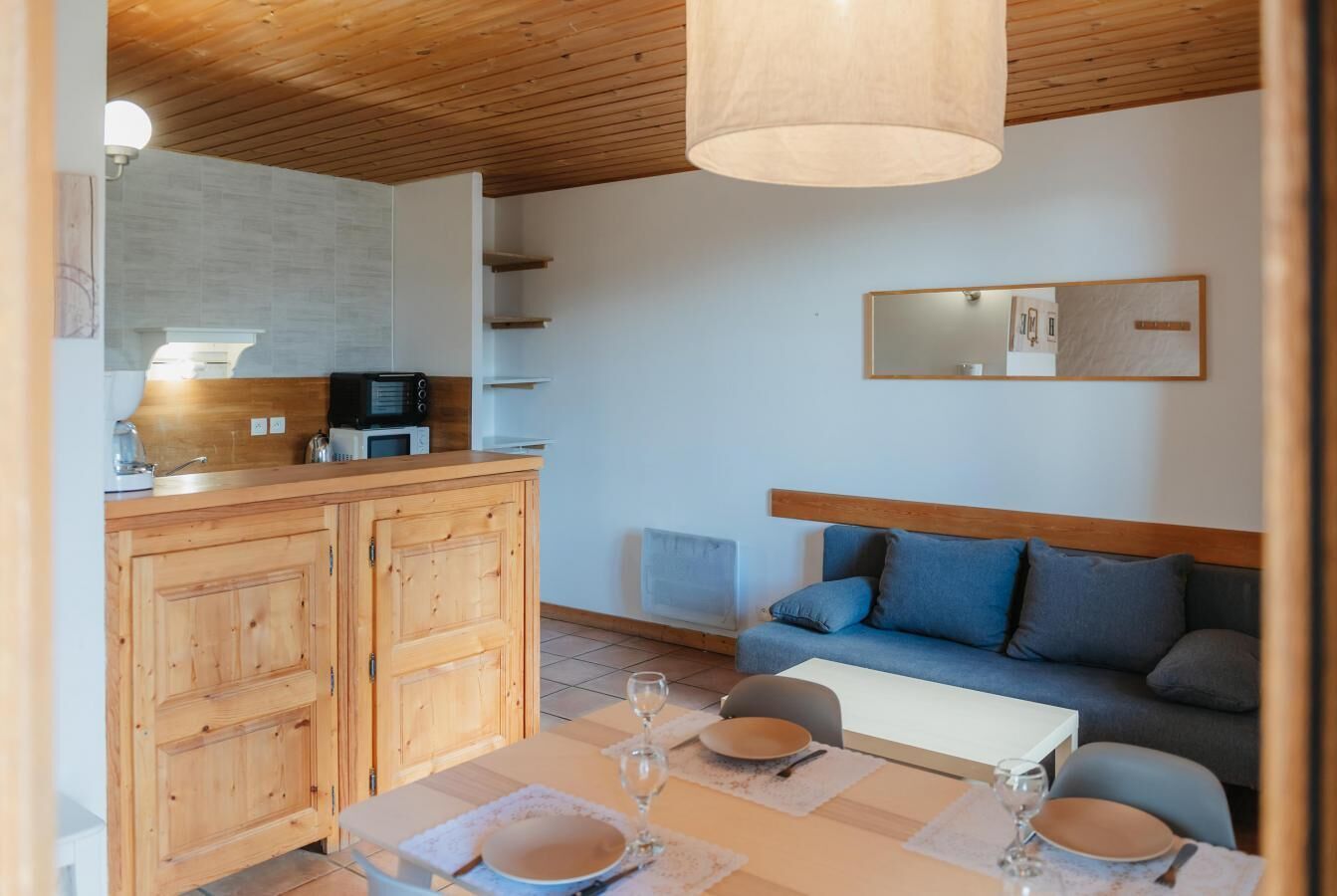 A compact living space with a kitchenette, a dining area, and a sofa.
