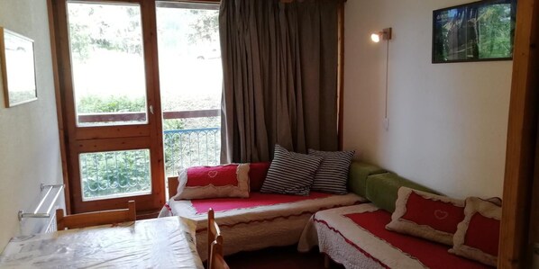 A cozy room with a bed, a small table, and a window with curtains.
