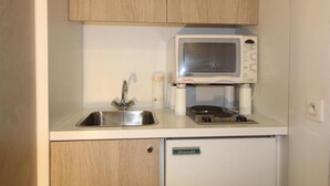 Une petite cuisine équipée avec un évier en acier inoxydable, un four à micro-ondes et un petit réfrigérateur.